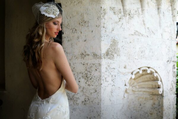A woman in a wedding dress leaning against a stone wall.