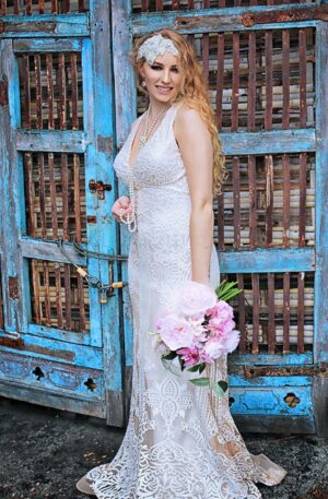 A woman in a wedding dress is standing in front of a blue door.