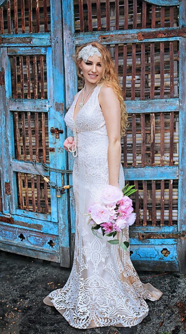 A woman in a wedding dress is standing in front of a blue door.