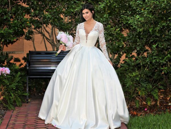 A woman in a white wedding dress is posing on a bench.