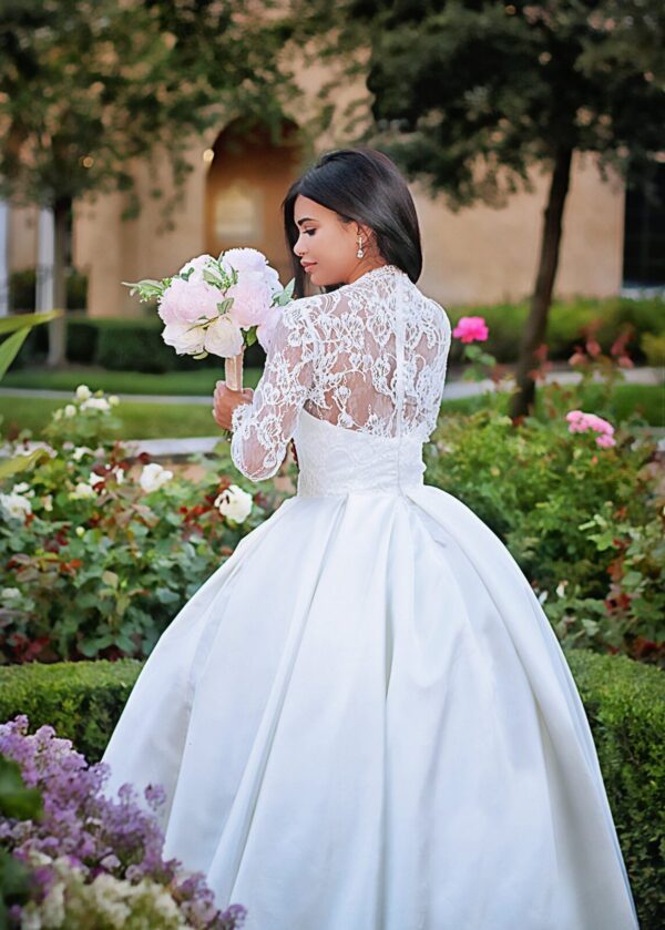 A bride in a white wedding dress standing in a garden.