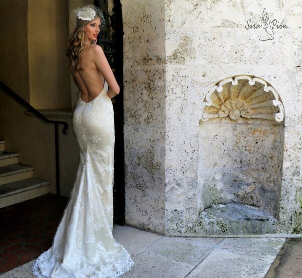 A woman in a wedding dress posing in front of an archway.