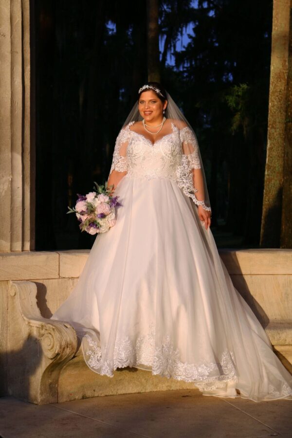 A woman in a wedding dress is posing in front of a fountain.
