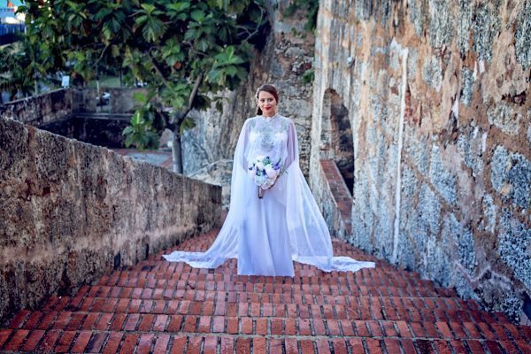 A bride in a white dress standing on a brick staircase.