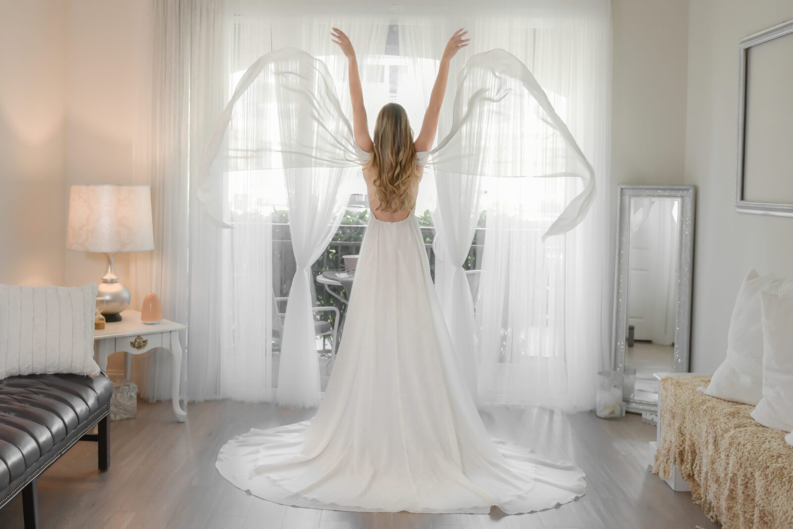 A bride in an Orlando custom design wedding dress standing in front of a window.