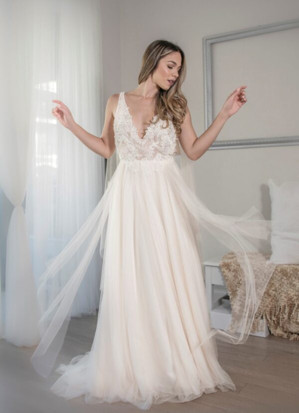 A woman in a Romantic Netting A-line Bridal Gown is standing in a room.