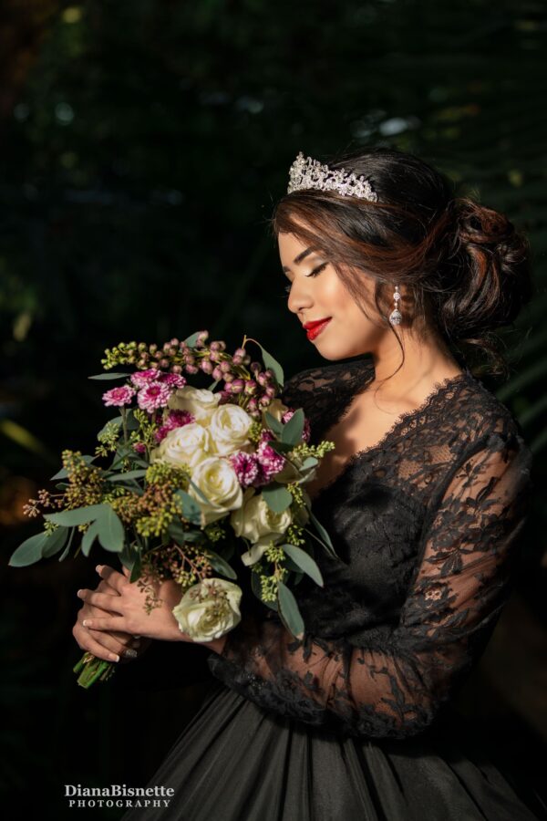 Beautiful bide wearing a long sleeve black gown smelling her roses