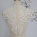 The back of a mannequin with a white lace appliqué.