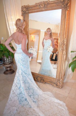 A Florida bride in a blue wedding dress is standing in front of a mirror.