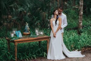 A bride and groom standing next to a table in the woods during their Florida wedding.