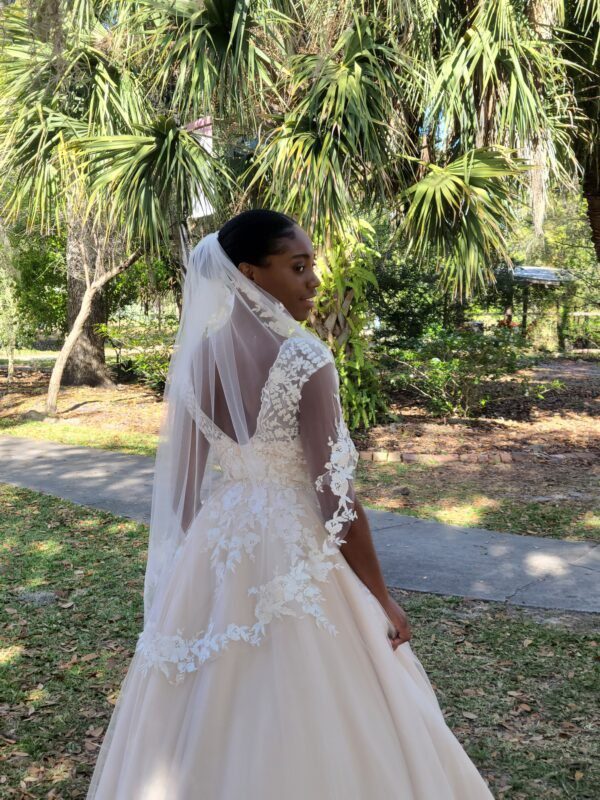A bride in a wedding dress standing in a park.