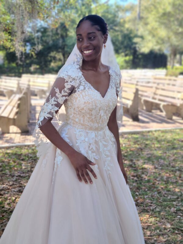 A black woman in a wedding dress standing in a park.