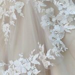 A close up of a wedding dress with lace and a handmade veil.