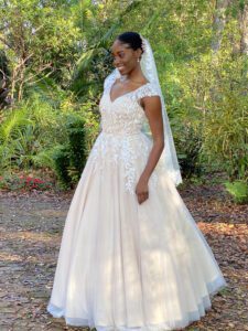 A black woman in a wedding dress standing in the woods.
