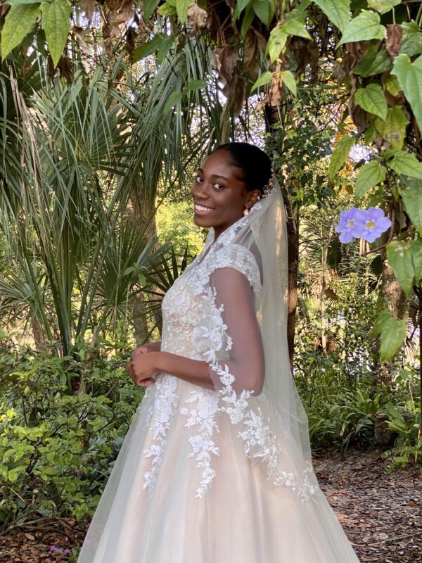 A black woman in a wedding dress poses for a picture.