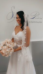 A bride in a wedding dress holding a bouquet and wearing a bridal veil.