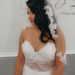 A bride in a wedding dress is standing in front of a wall.