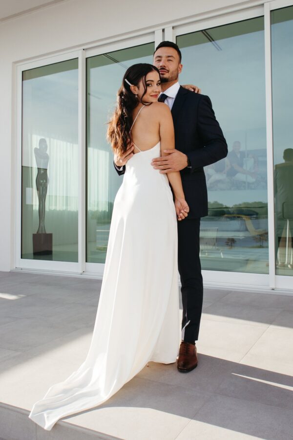 A bride and groom embracing in front of a glass door, providing wedding dress inspiration.