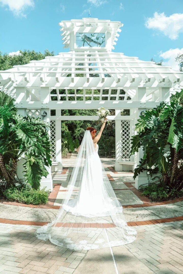 A bride showcasing her stunning Orlando wedding dress in front of a white gazebo.