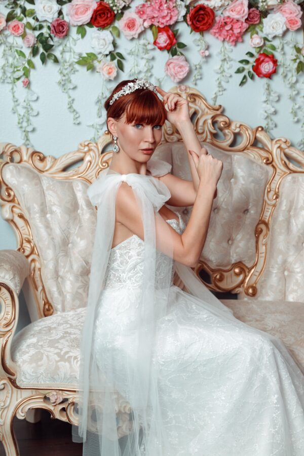 A beautiful woman in a wedding dress sitting on a couch, showcasing the elegance of bridal gowns and wedding dresses.