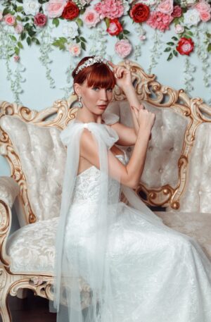 A beautiful woman in a wedding dress sitting on a couch, showcasing the elegance of bridal gowns and wedding dresses.