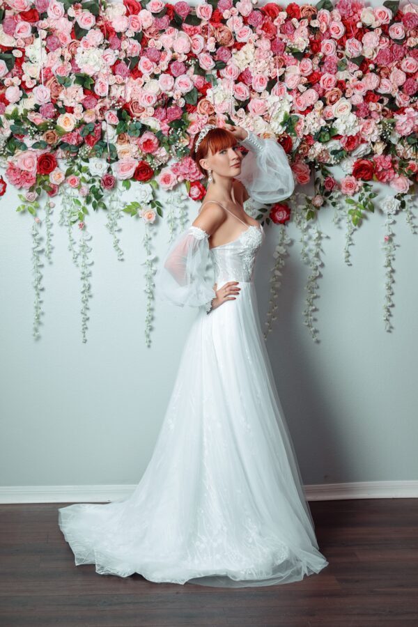 A beautiful bride in a Orlando wedding dress posing in front of a flower wall.