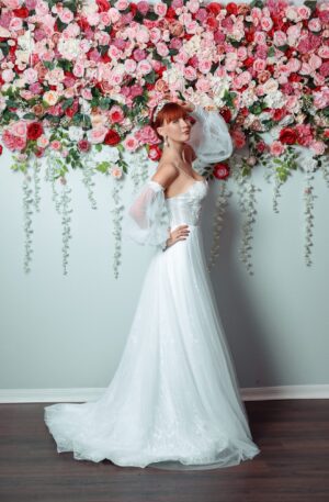 A beautiful bride in a Orlando wedding dress posing in front of a flower wall.