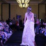 A woman is strutting down the runway at a bridal fashion show.