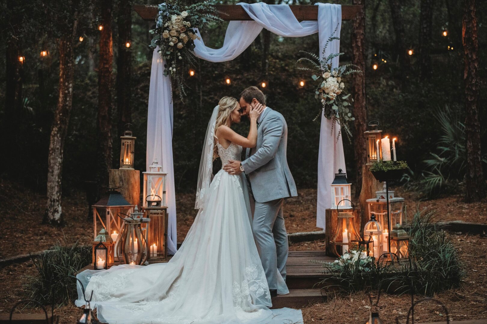A fairy tale bride and groom share a romantic kiss amidst the enchanting woods during their wedding ceremony. The bride looks exquisite in her princess wedding dress.